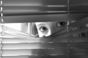 Image of woman looking out of blinds at stalker